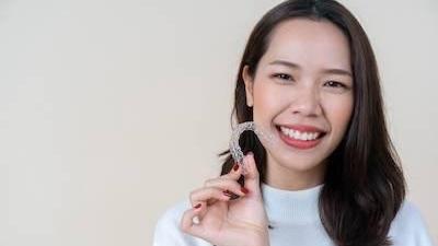 woman holding clear plastic aligner in Seattle WA
